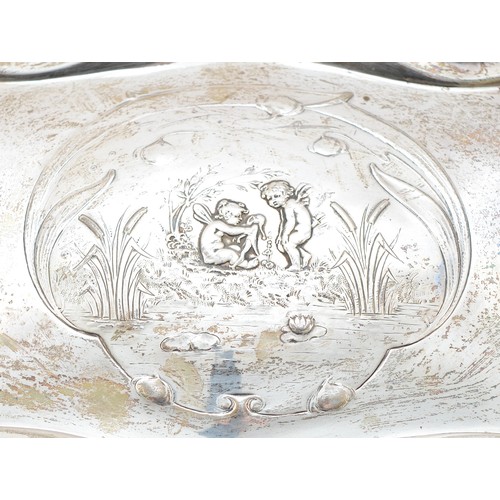20 - An Edwardian silver tray, Chester 1905, having serpentine border and embossed Cherub scene to the ce... 