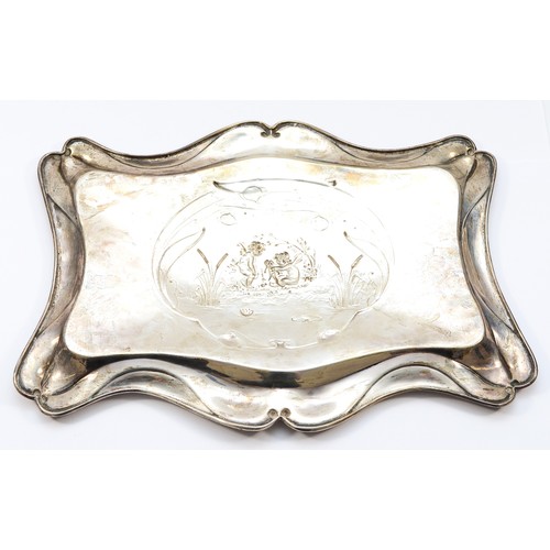20 - An Edwardian silver tray, Chester 1905, having serpentine border and embossed Cherub scene to the ce... 
