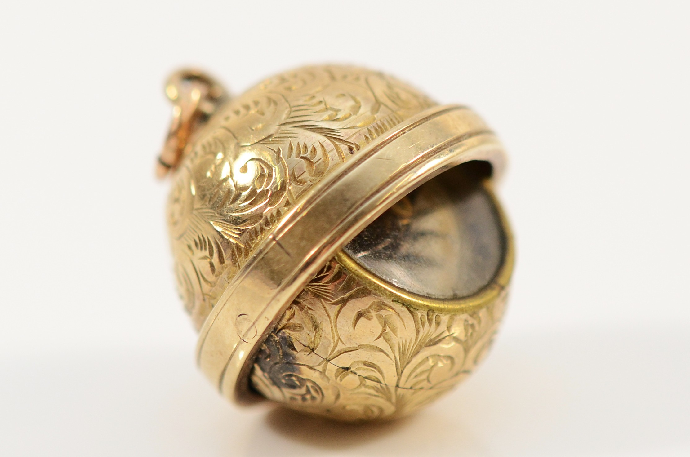 A 9ct gold engraved orb charm that spins to reveal a compass, 15mm, 5.4g