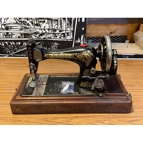 A Singer manual wind sewing machine, in oak case, together with three ...