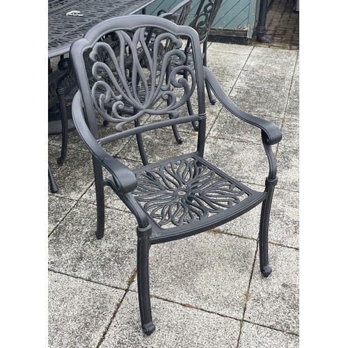 48 - A large cast-aluminum garden table with six matching chairs and an umbrella, 221cm x 75.