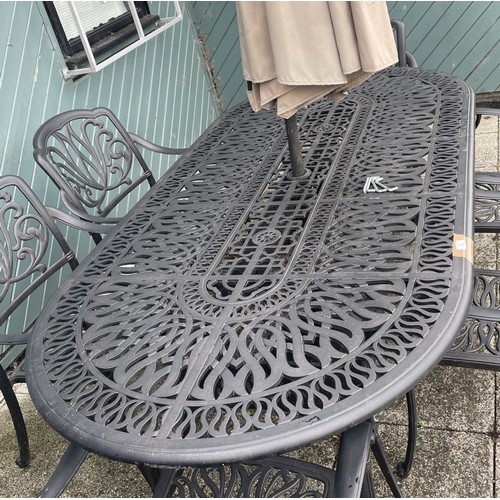 48 - A large cast-aluminum garden table with six matching chairs and an umbrella, 221cm x 75.