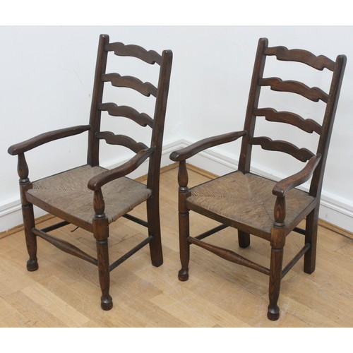 21 - Two children's oak carver chairs with curved armrests, a ladder back and rush seats, raised on turne... 