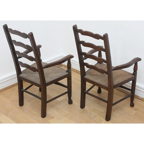 21 - Two children's oak carver chairs with curved armrests, a ladder back and rush seats, raised on turne... 
