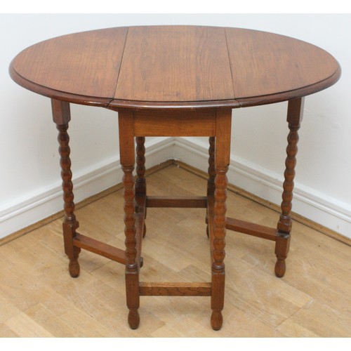 24 - An Edwardian oak drop-leaf side table, gateleg action  oval form top, supported on bobbin turned leg... 