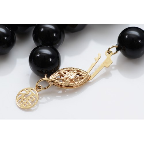 48 - A 14K gold clasped black onyx beaded necklace, 66cm