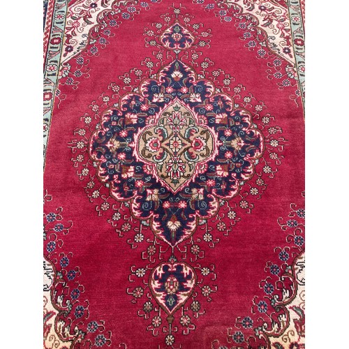 425 - A Persian Tabriz rug; Northwest Iran, in a palette of crimson, blue, cream and pale green with centr... 