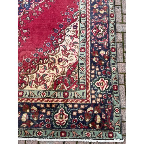 425 - A Persian Tabriz rug; Northwest Iran, in a palette of crimson, blue, cream and pale green with centr... 