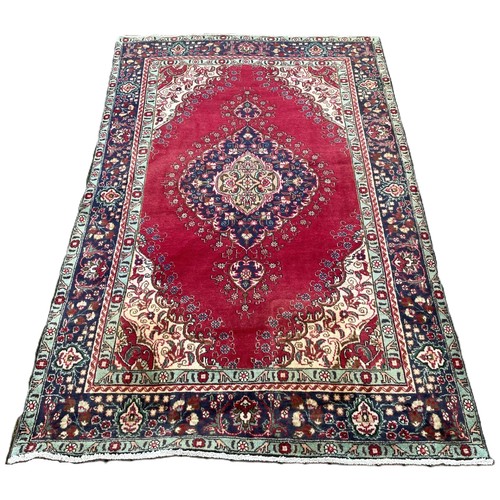425 - A Persian Tabriz rug; Northwest Iran, in a palette of crimson, blue, cream and pale green with centr... 