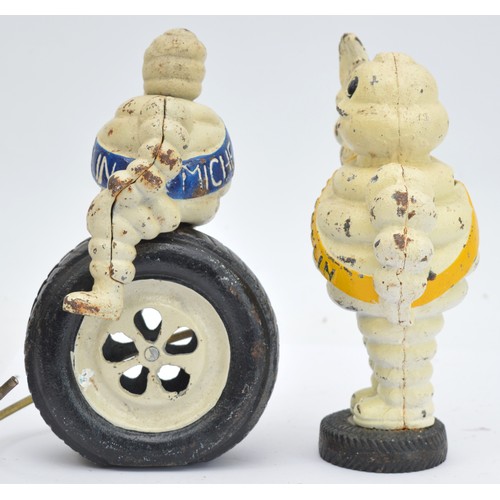 40 - A painted cast iron Michelin man riding a wheel, 24cm and another waving (2).