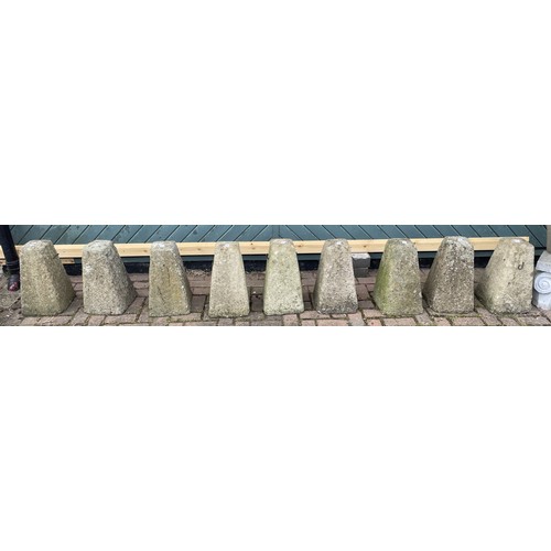 Nine reconstituted concrete garden bollards, each measuring approximately 45cm high on a 25cm square base, with old/detached fittings for chains.