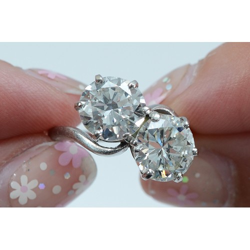  A circa 1940 unmarked platinum two stone cross over ring, two early brilliant cut diamonds weighed o... 