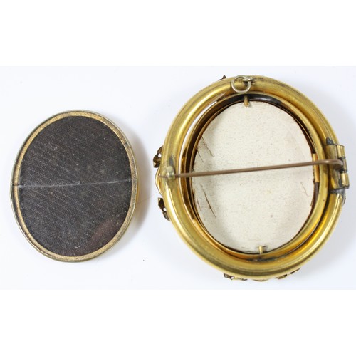 58 - A gold plated shell cameo spinning brooch, the Three Graces to one side and an opening locket to the... 