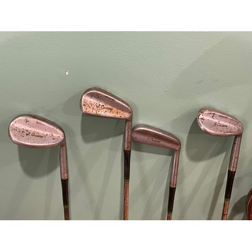 34 - A group of vintage golf clubs, including woods and irons in canvas and leather golf bag.