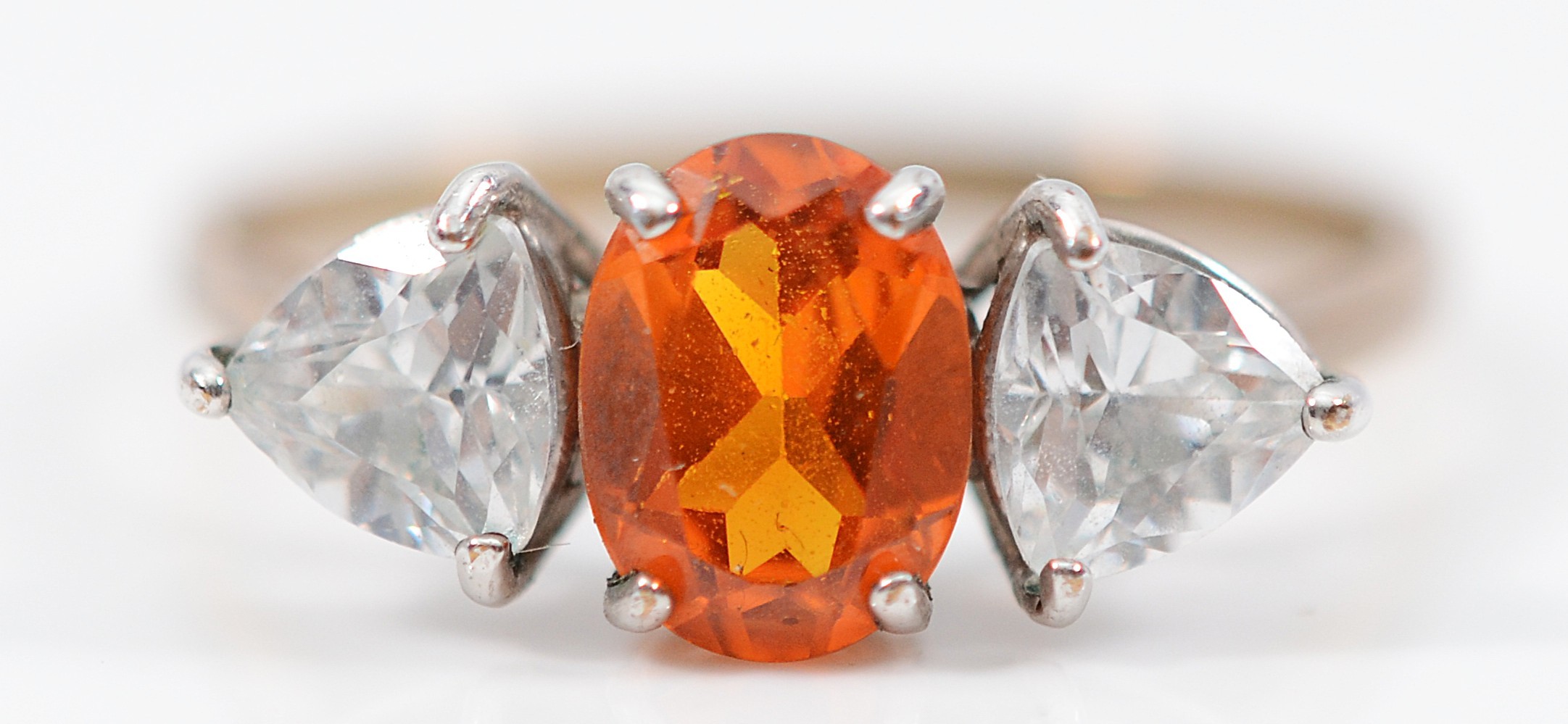 A 9ct gold synthetic orange sapphire and white gemstone three stone ...