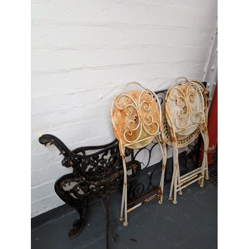513 - A pair of cast iron bench ends and garden table with chairs