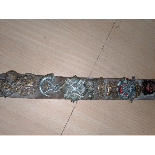 465 - A German belt with a collection of military cap badges attached, plus ribbons,cloth badges, German L... 