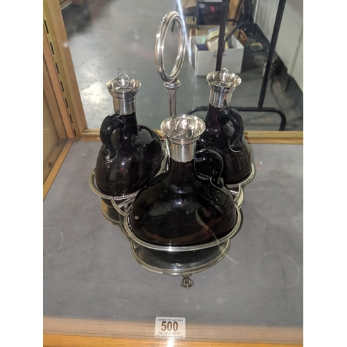 500 - A set of three hallmarked silver capped dark amber glass decanters on hallmarked solid silver trifor... 