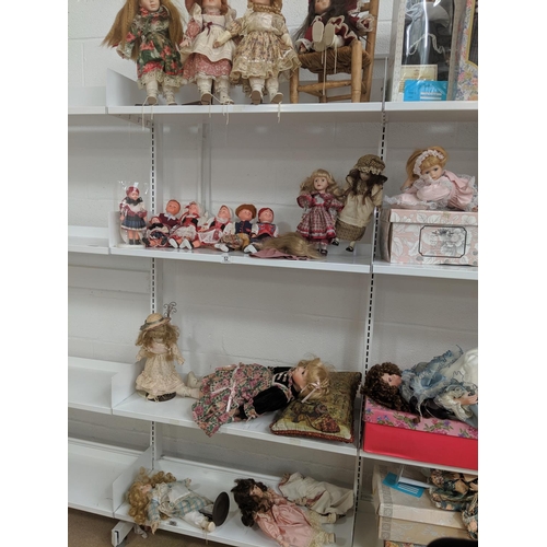 52 - Four shelves of dolls including porcelain faced, dolls on stands etc.