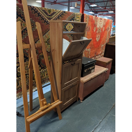 770 - An easel, tall cabinet, wicker ottoman and basket and metal box