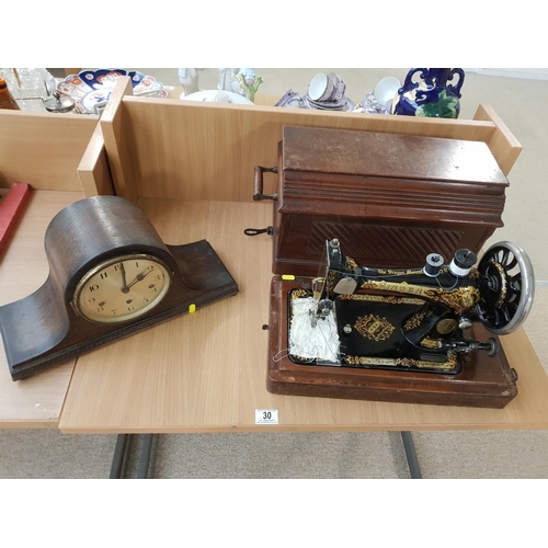 30 - A Singer hand crank sewing machine in wooden case and a mantle clock