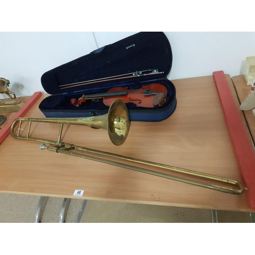 48 - A violin in case and brass trombone