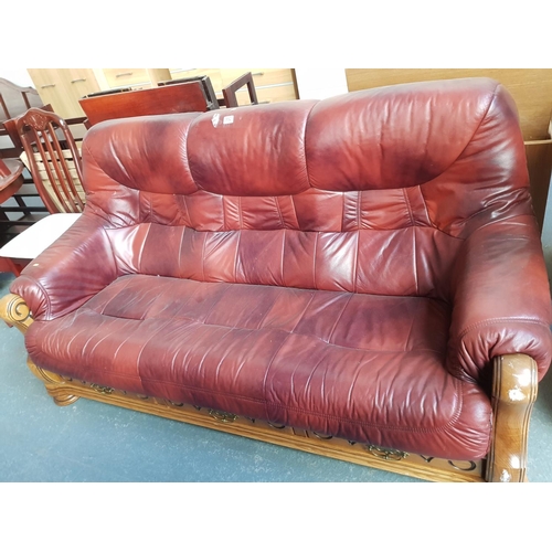 552 - A wooden framed red leather three seater sofa.