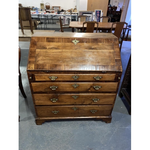 128 - A Georgian walnut writing bureau with fitted interior and four drawers