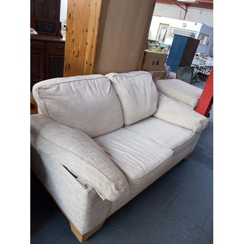 356 - A cream two seater sofa and two footstools