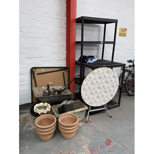 593 - Mixed garden items to include pots and planters, wheelbarrow, plastic shelving etc.