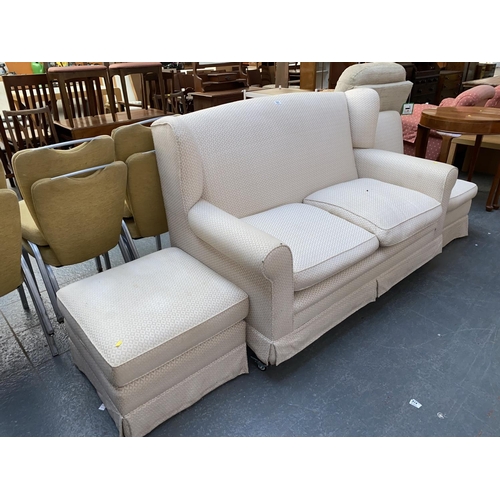 523 - A cream fabric two seater sofa with matching armchair and footstool