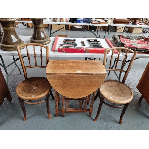 103 - A small oak drop leaf table on barley twist supports and two bentwood style chairs