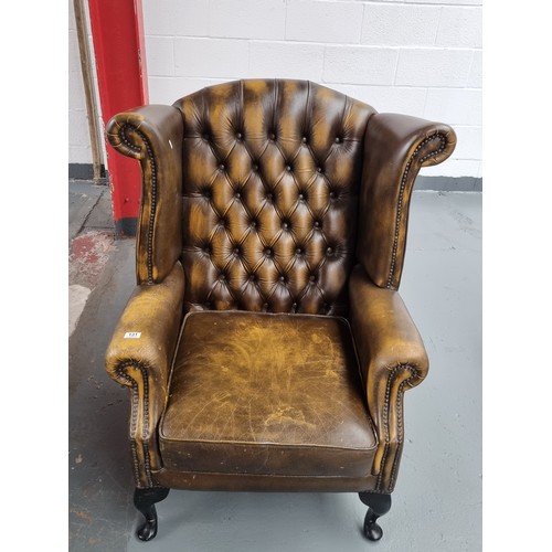 131 - A golden/brown Chesterfield wingback armchair