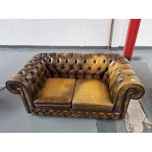 132 - A golden/brown Chesterfield two seater sofa