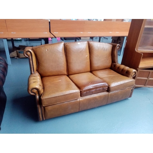 112 - A tan leather Chesterfield style three seater settee