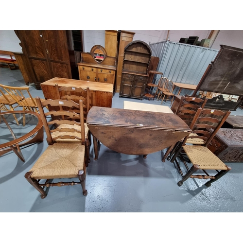 119 - An early oak drop leaf dining table and four ladder back rush seated dining chairs