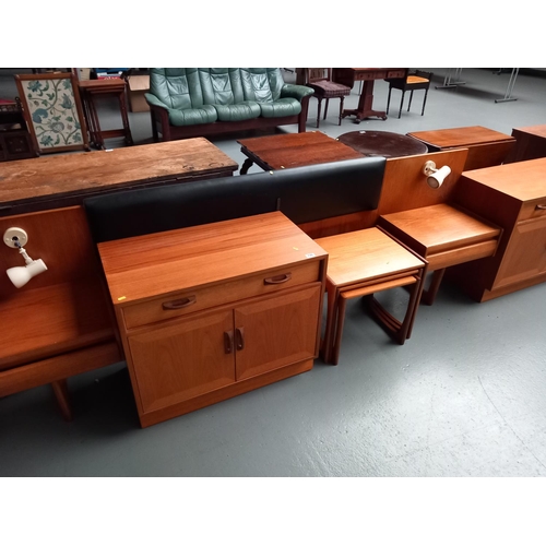 135 - A collection of teak GPlan furniture consisting of a headboard, two cupboards and a nest of tables