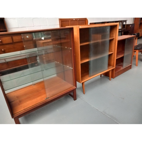 139 - A teak glass fronted Turnidge display cabinet with two over teak glass fronted display cabinets