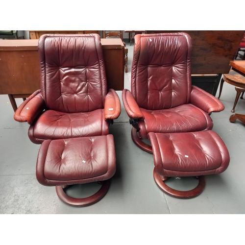 117 - Two leatherette swivel armchairs with matching footstools