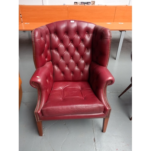 116 - A red leather chesterfield style wingback armchair