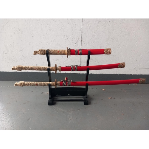 208 - A set of three ornamental samurai swords on wooden stand (collection only  - no postage)