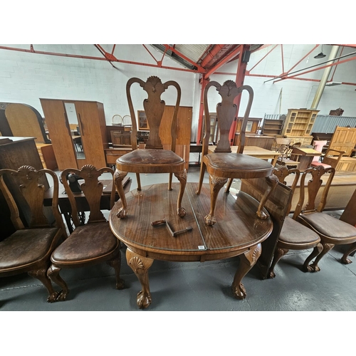 103 - An extending oval mahogany dining table with one extra leaf, hand crank and six dining chairs