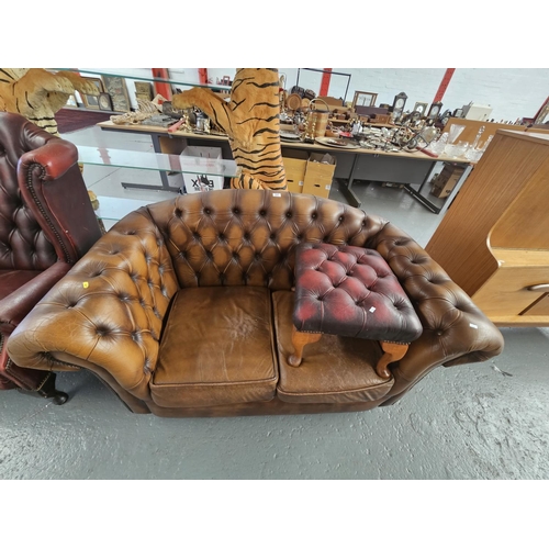 107 - A brown leather Chesterfield two seater sofa together with a red leather Chesterfield stool