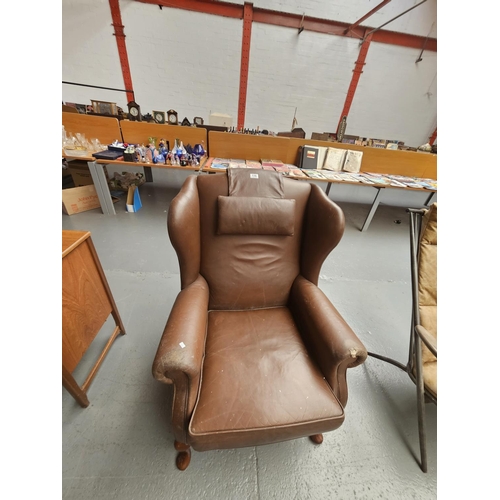 110 - A brown leather wingback armchair