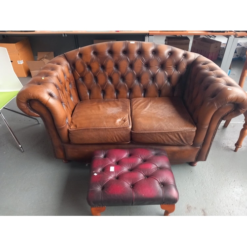 101 - A brown leather Chesterfield two seater sofa together with a red leather Chesterfield footstool