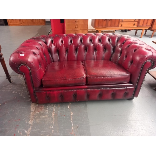 121 - A red leather chesterifeld two seater sofa