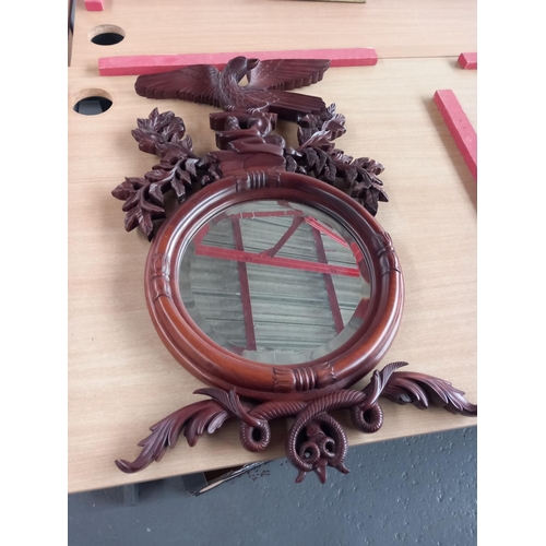 72 - A circular mirror in a carved wooden frame with eagle decoration