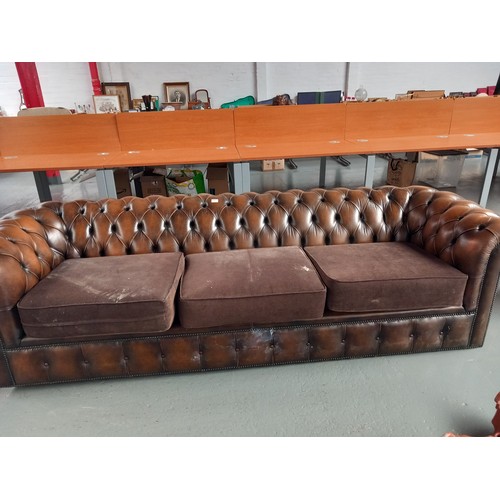 107 - A brown leather fabric cushioned chesterfield style three seater sofa