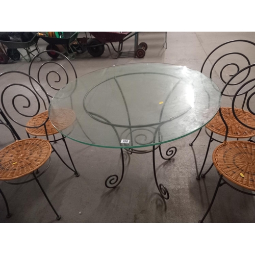 636 - A circular glass topped metal based dining table with four rush seated metal framed chairs