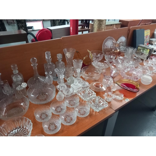 140 - A quantity of crystal, pressed and coloured glass - decanters, vases, bowls etc